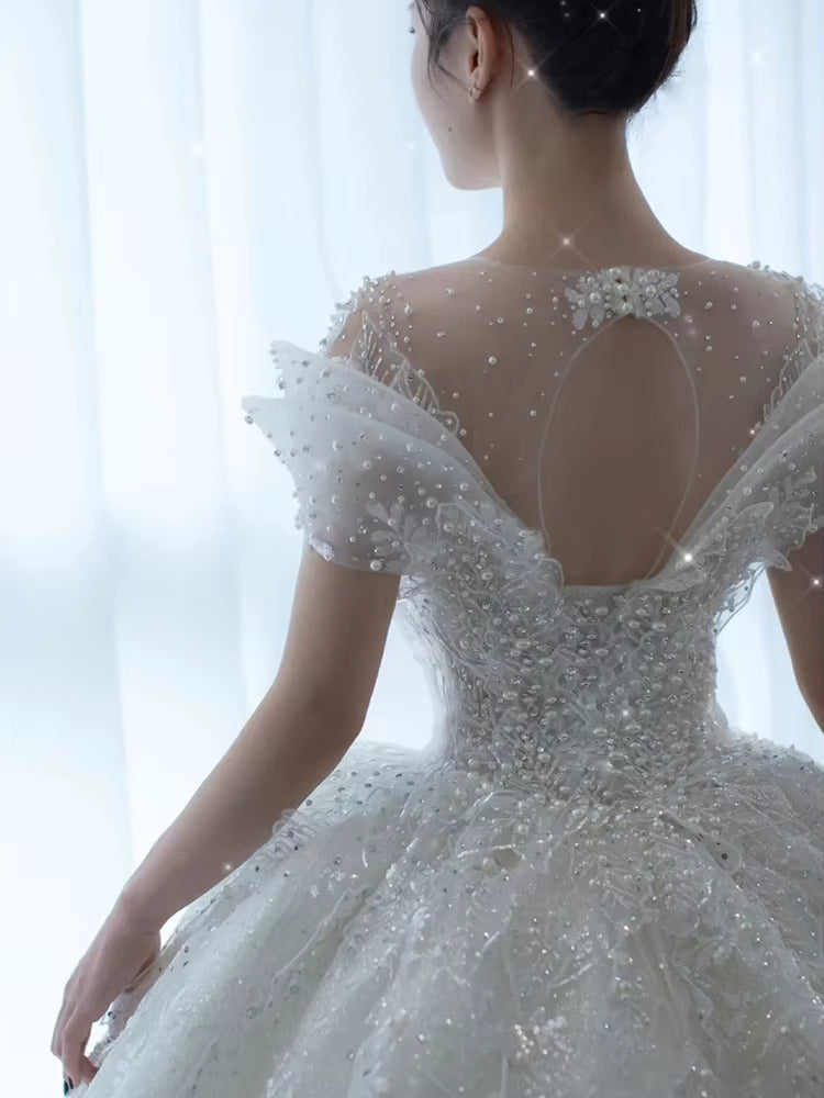 Back view of a person wearing an elegant white wedding dress with intricate detailing.