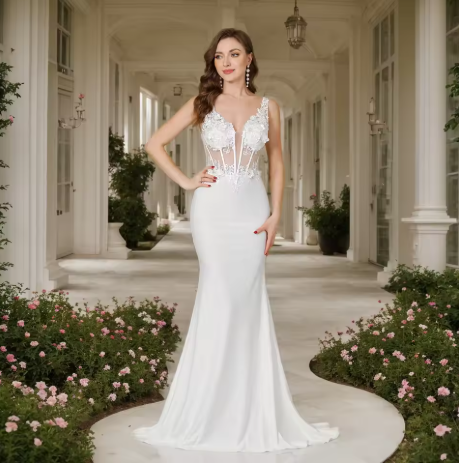 Woman in a white wedding dress standing in a elegant outdoor setting with flowers and columns.