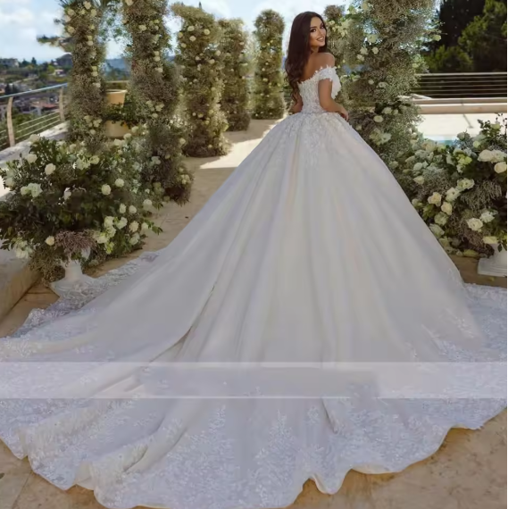 Woman in a white wedding dress standing in front of floral decorations.